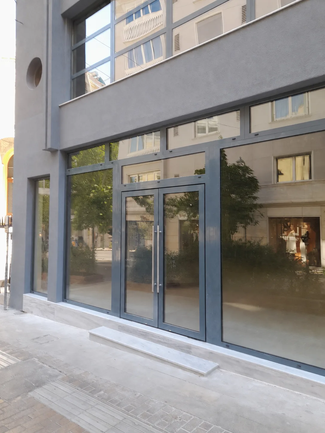 A shopfront with dark grey aluminium frames and a double pivot door, Kolonaki